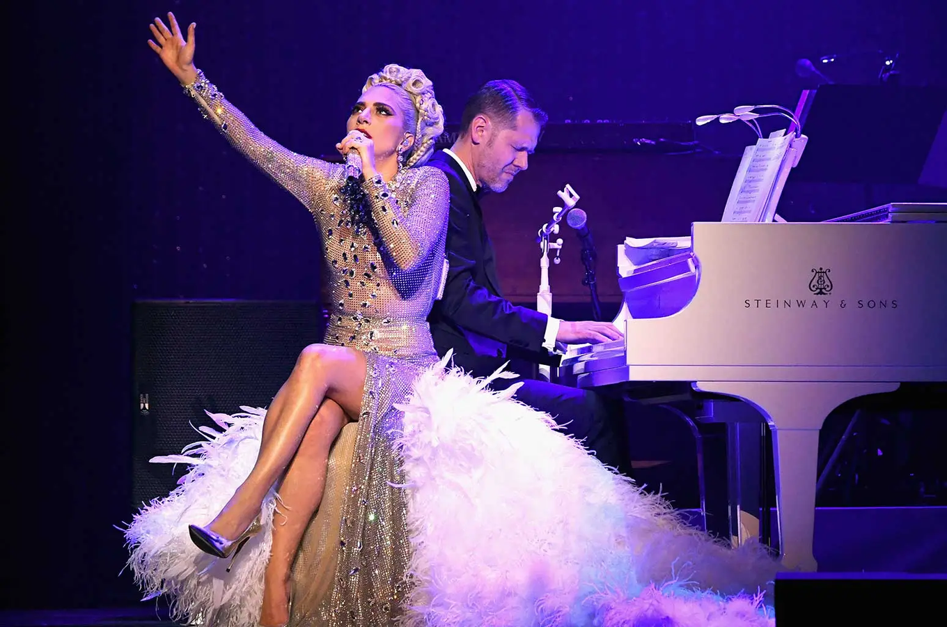 Lady Gaga sings by piano in 2019 show.